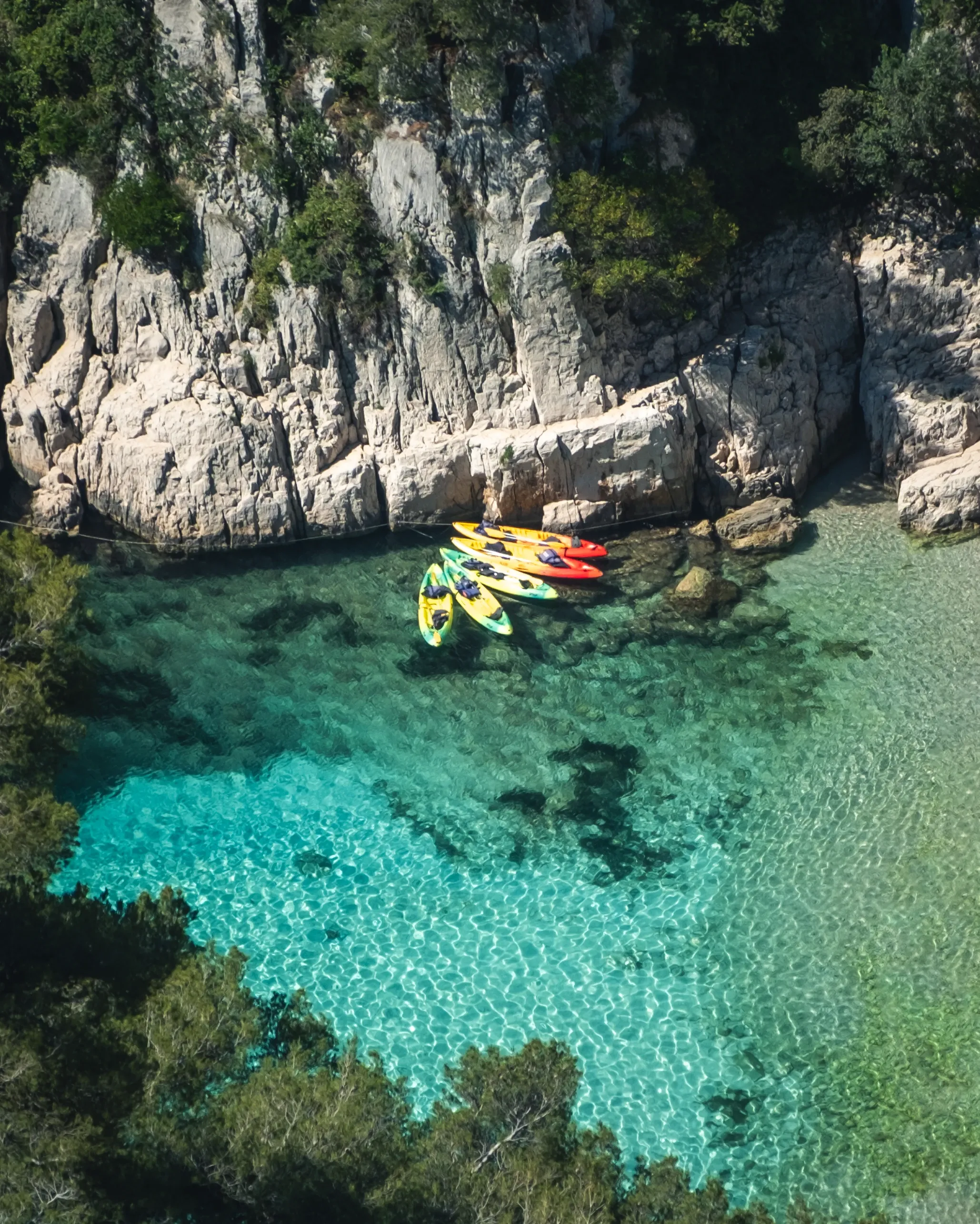 Colorful kayaks moored in a turquoise cove below white cliffs