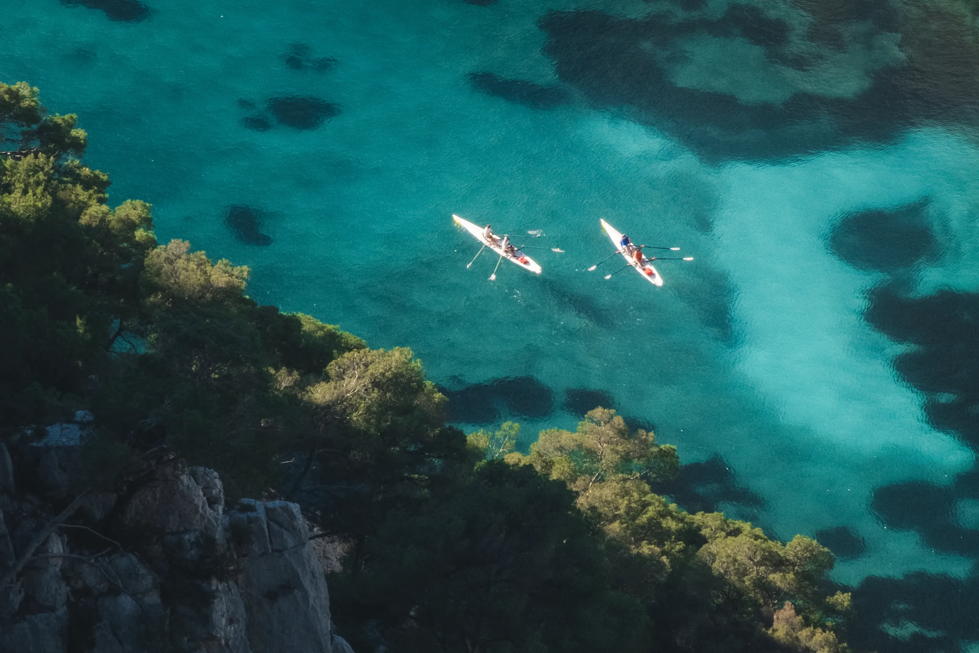 Two kayaks on turquoise water over seagrass, seen from above